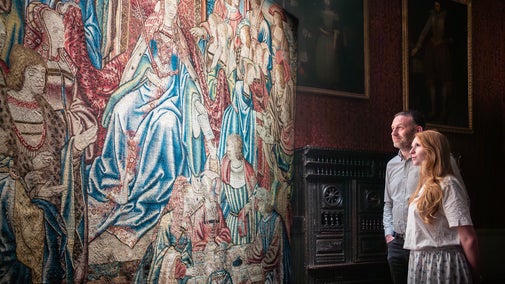 An image of two visitors looking at the Queen Esther tapestry at Oxburgh Estate in Norfolk